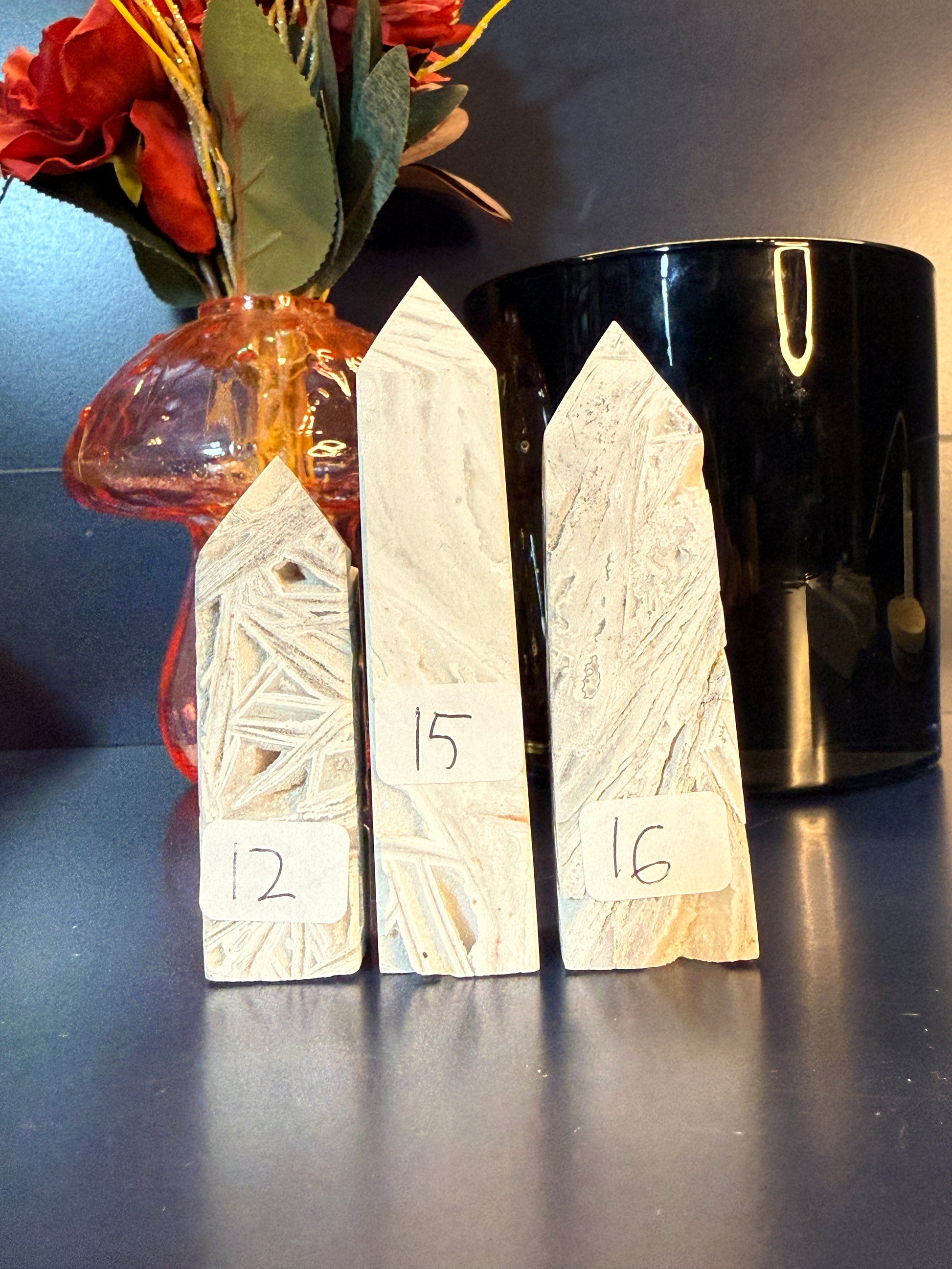 Three white crystal towers with lattice patterns sitting in front of a mushroom vase and black jar