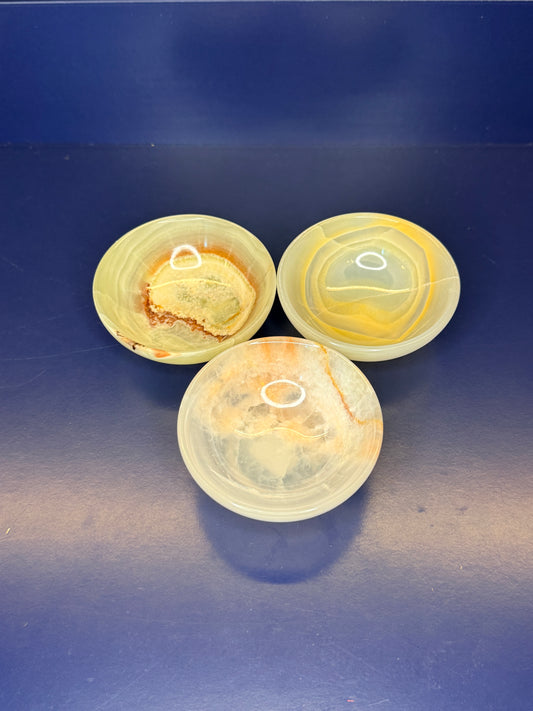 Three light green onyx bowls on a dark blue background