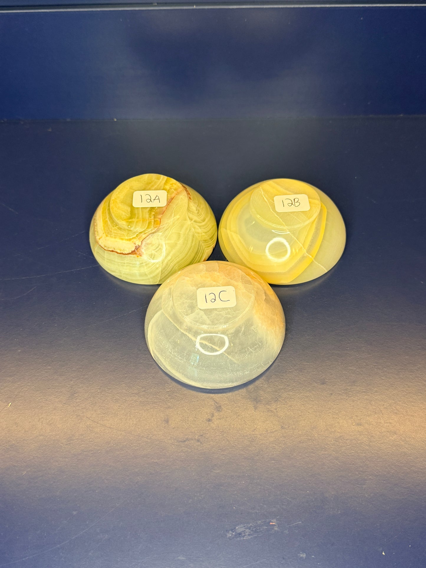 Three light green onyx bowls with labels on a dark blue background