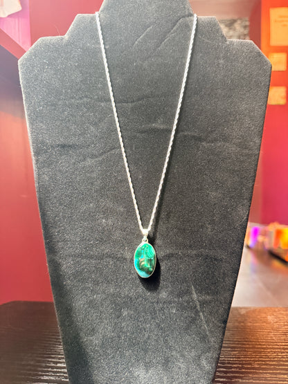 Sterling silver necklace resting on a black velvet jewelry stand holding a green and blue malachite and chrysocola pendant 
