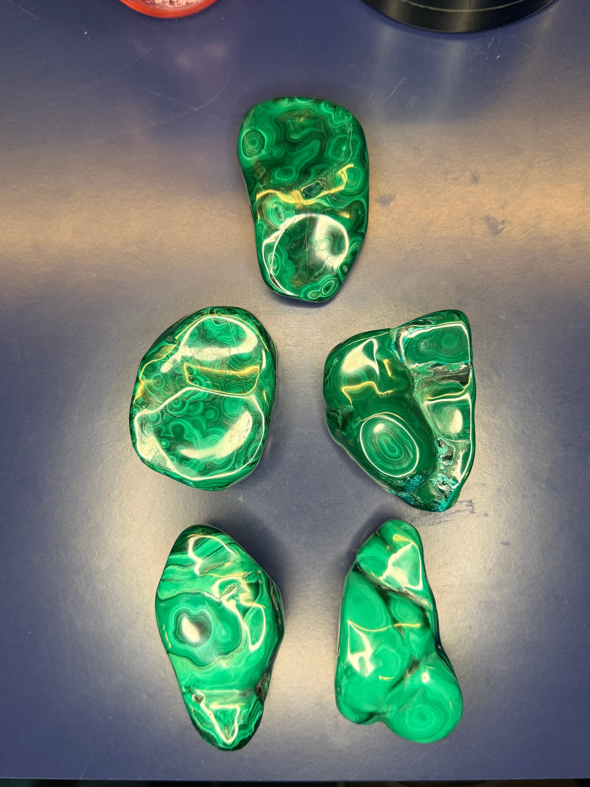Five green marbled malachite free forms on a blue background