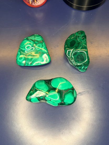 Three green marbled malachite free forms on a blue background