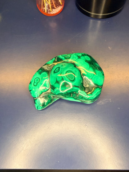 A large green marbled malachite free form on a blue background