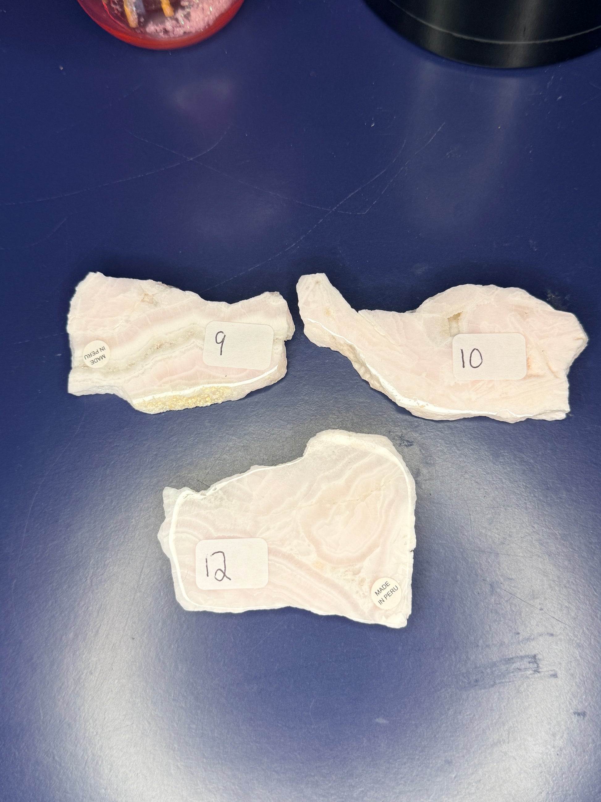 Three light pink and white mangano calcite slabs on a blue background