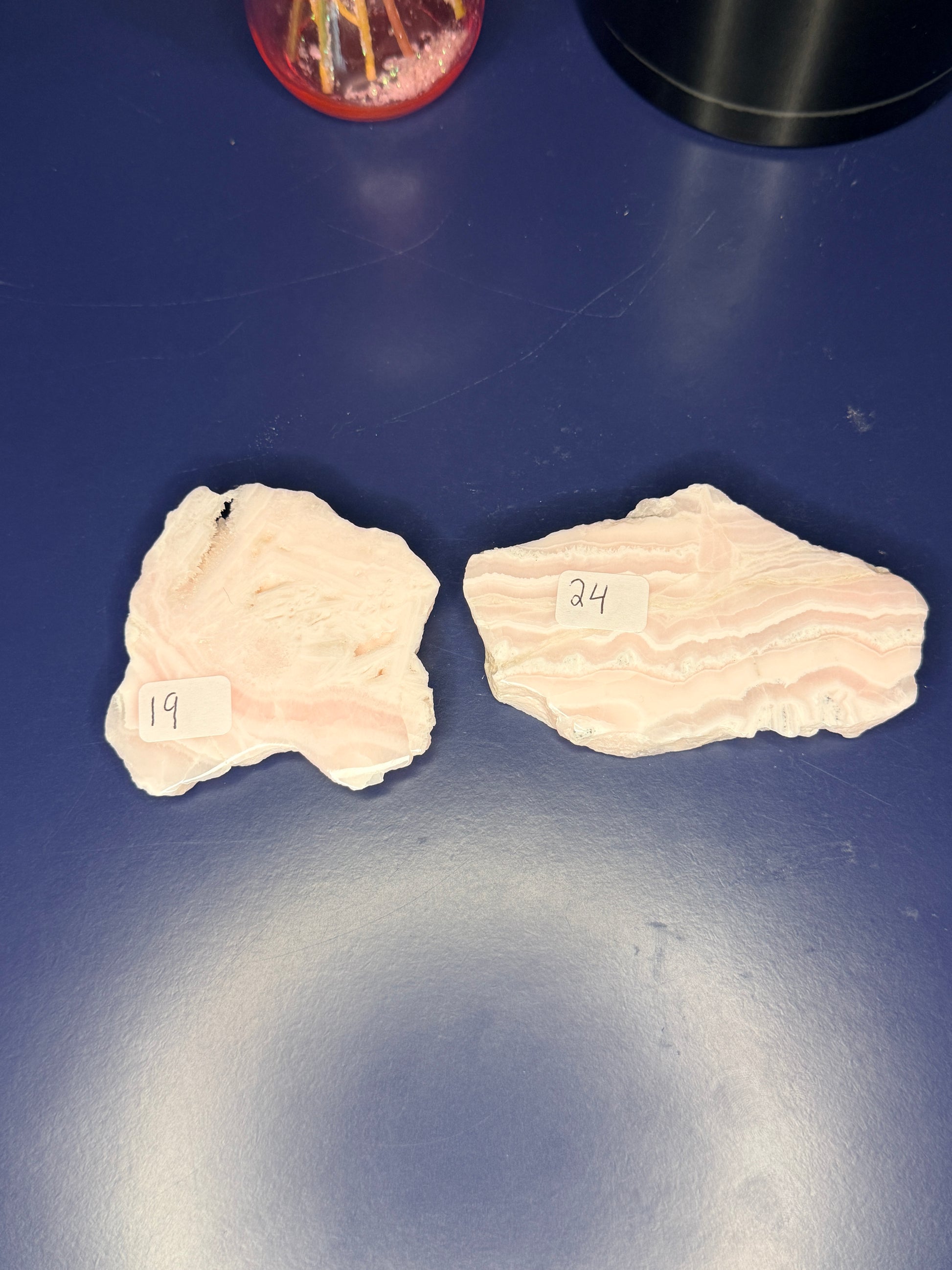 Two light pink and white mangano calcite slabs on a blue background