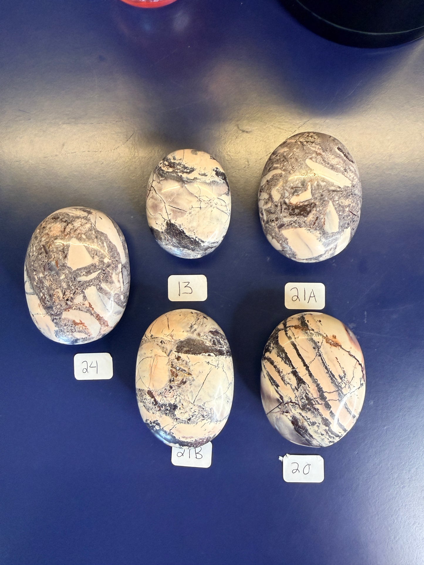 Five lightly colored mayan porcelain jasper palmstones on a blue background