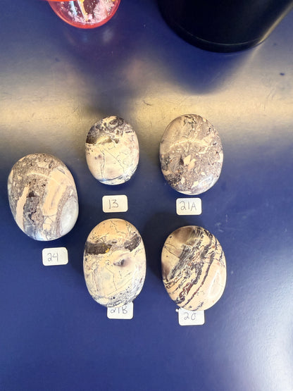 Five lightly colored mayan porcelain jasper palmstones on a blue background