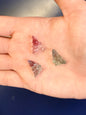 Hand holding three faerie shaped fluorite crystals on a blue background