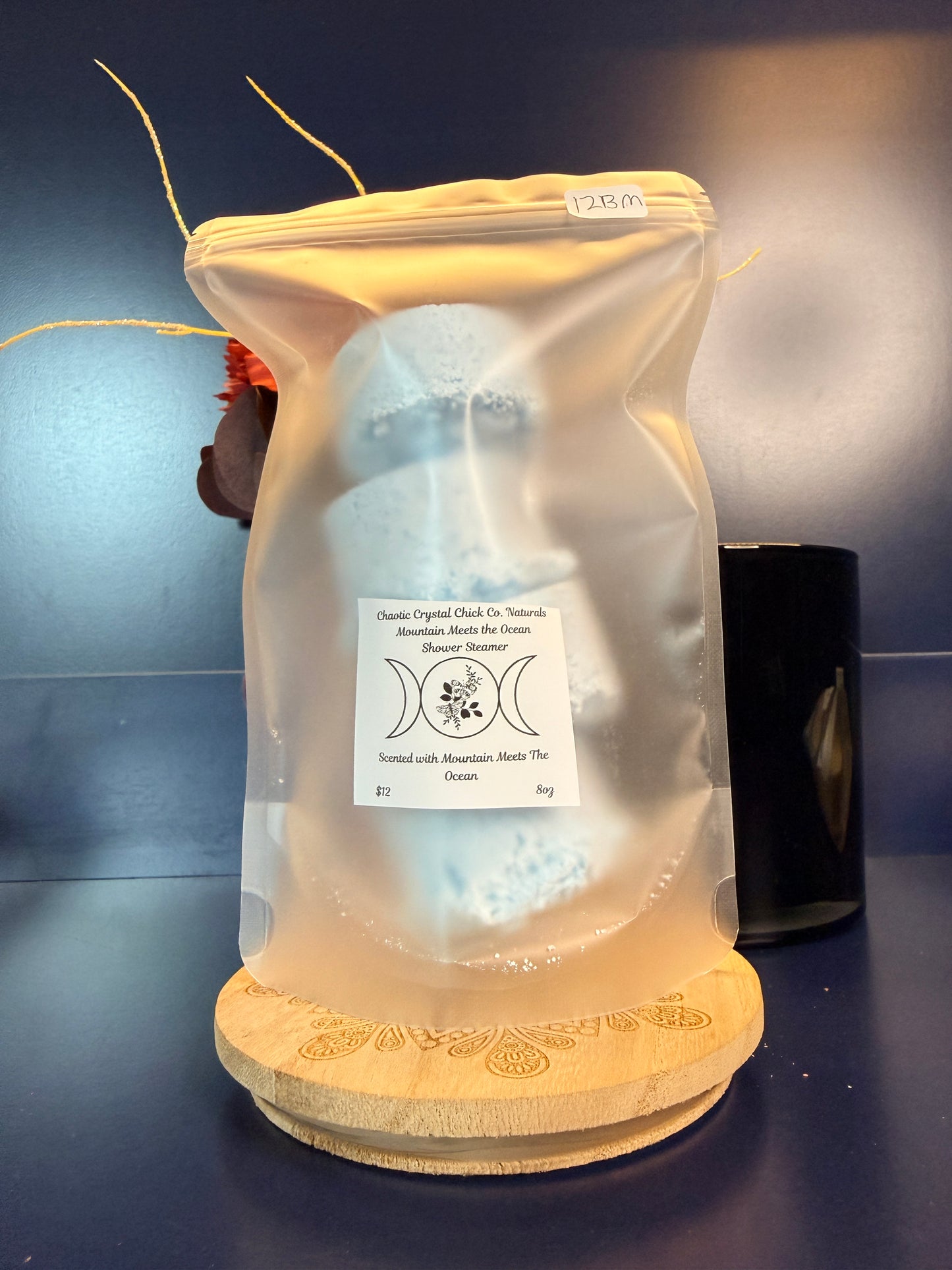 Packaged blue shower steamers on a decorative wooden coaster on a blue background