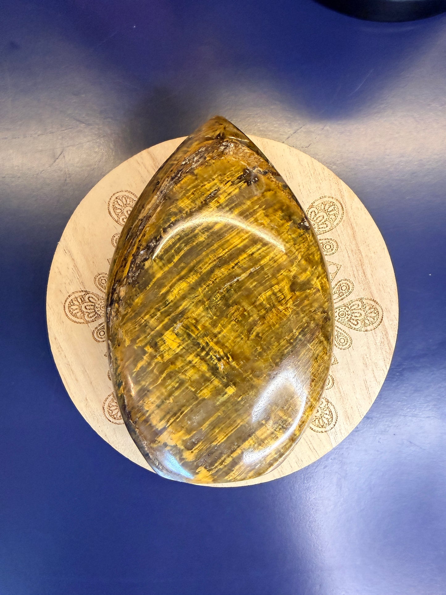 Gold nellite freeform on a wooden coaster against a blue background