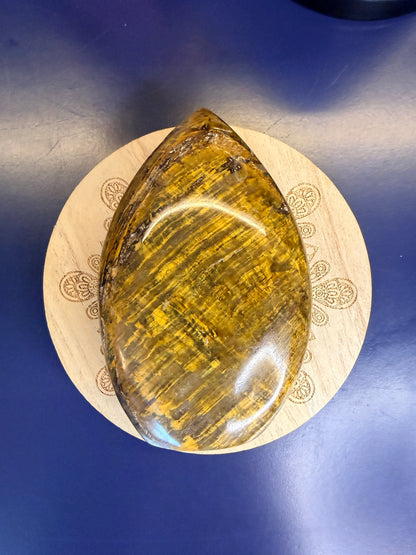 Gold nellite freeform on a wooden coaster against a blue background