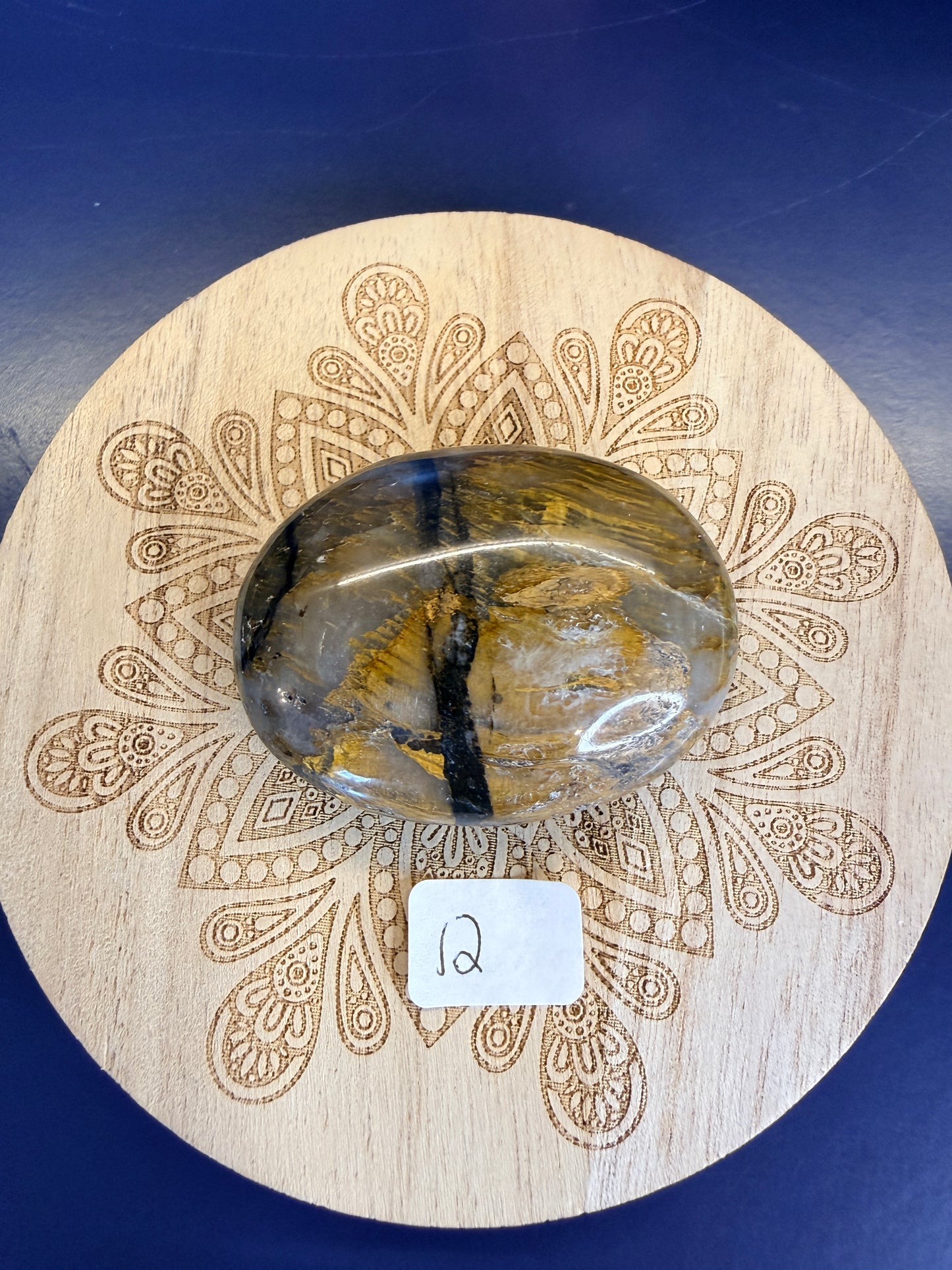 Decorative wooden coaster with a gold and clear nellite palmstone on a blue background