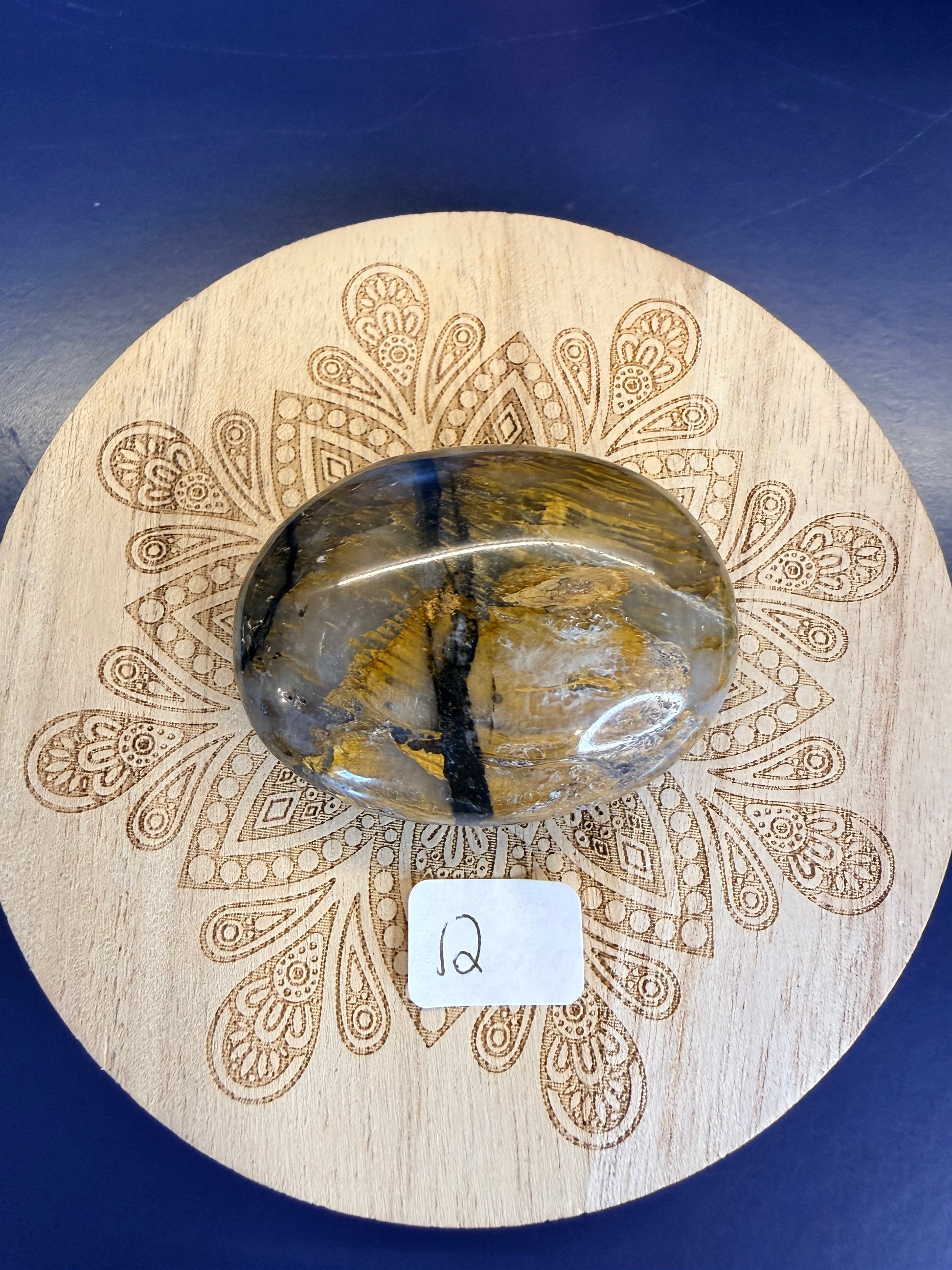 Decorative wooden coaster with a gold and clear nellite palmstone on a blue background
