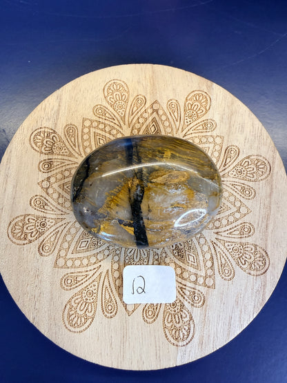 Decorative wooden coaster with a gold and clear nellite palmstone on a blue background