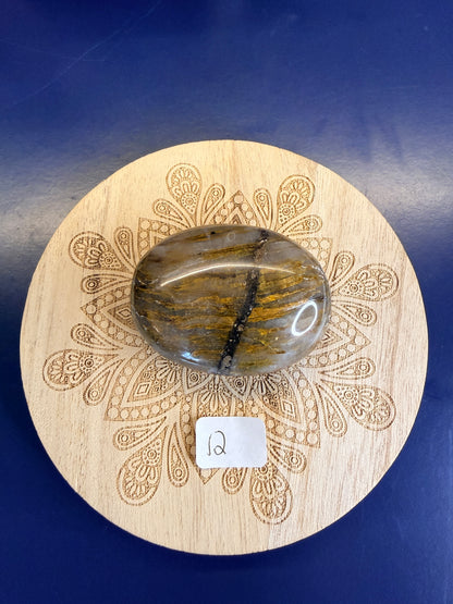 Decorative wooden coaster with a gold and clear nellite palmstone on a blue background