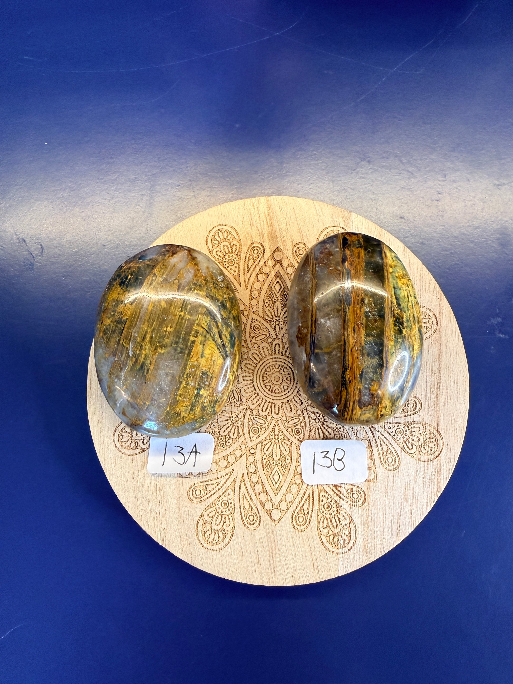 Decorative wooden coaster with two gold and clear nellite palmstones on a blue background