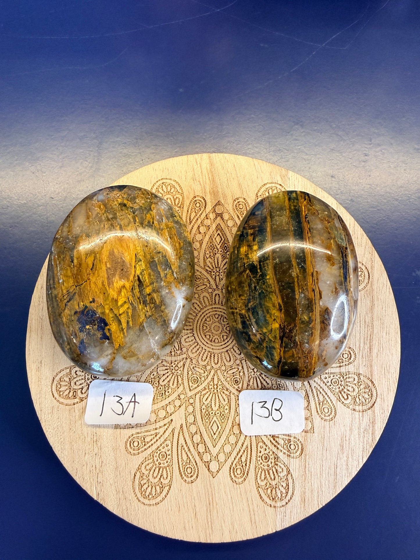 Decorative wooden coaster with two gold and clear nellite palmstones on a blue background