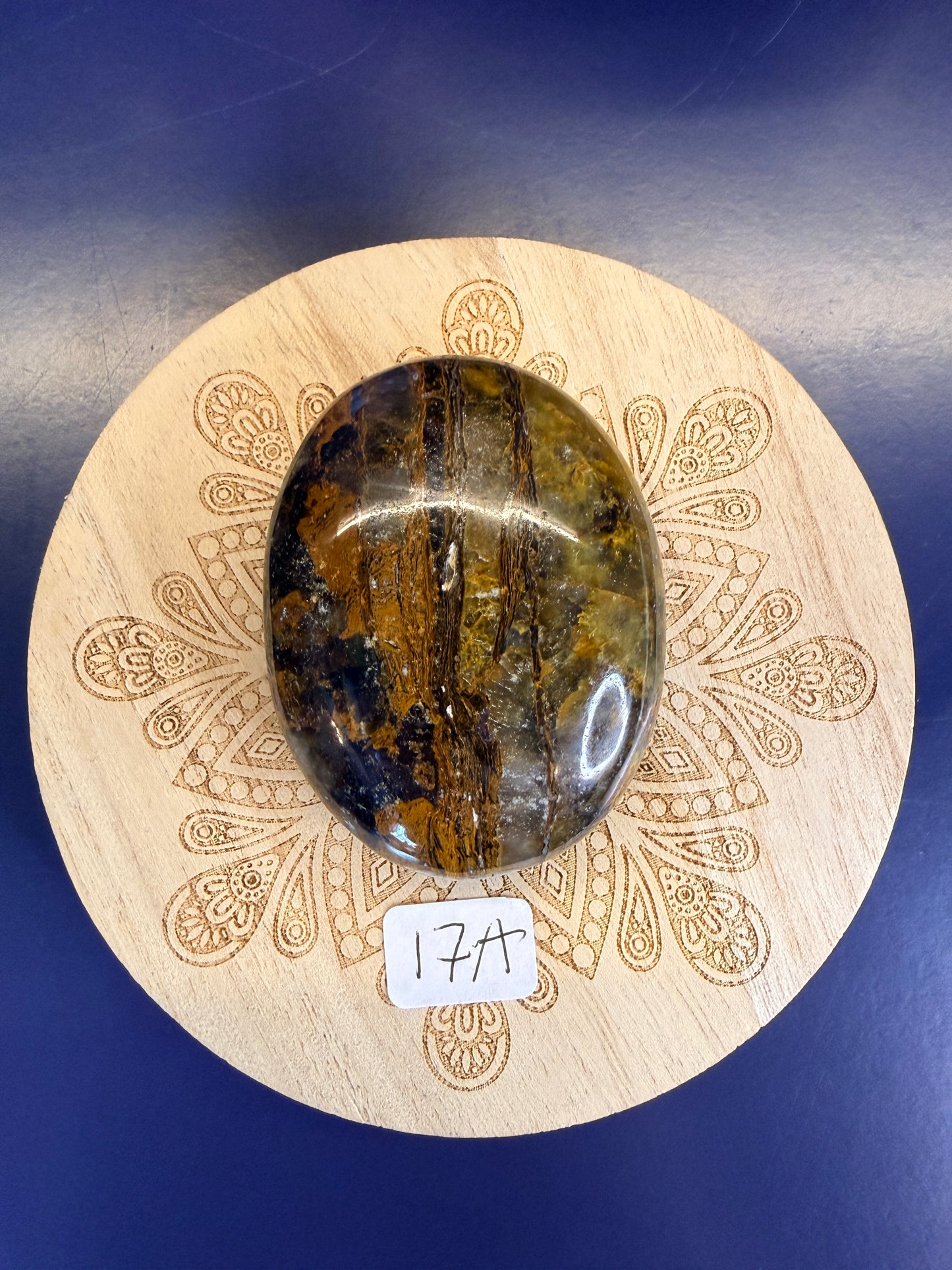 Decorative wooden coaster with a gold and clear nellite palmstone on a blue background