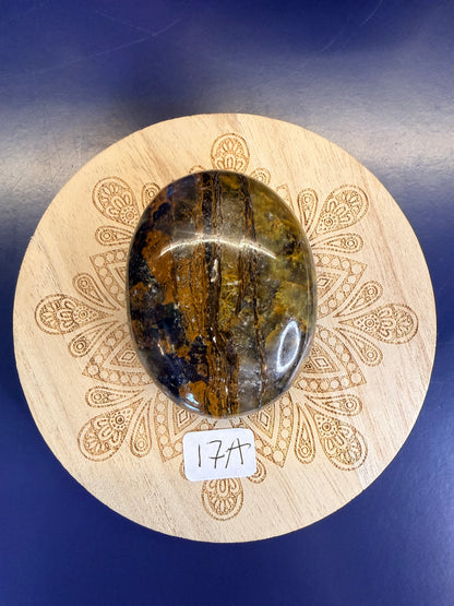 Decorative wooden coaster with a gold and clear nellite palmstone on a blue background