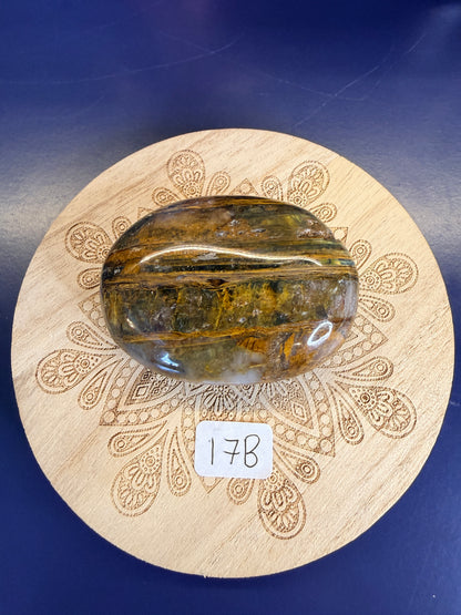 Decorative wooden coaster with a gold and clear nellite palmstone on a blue background