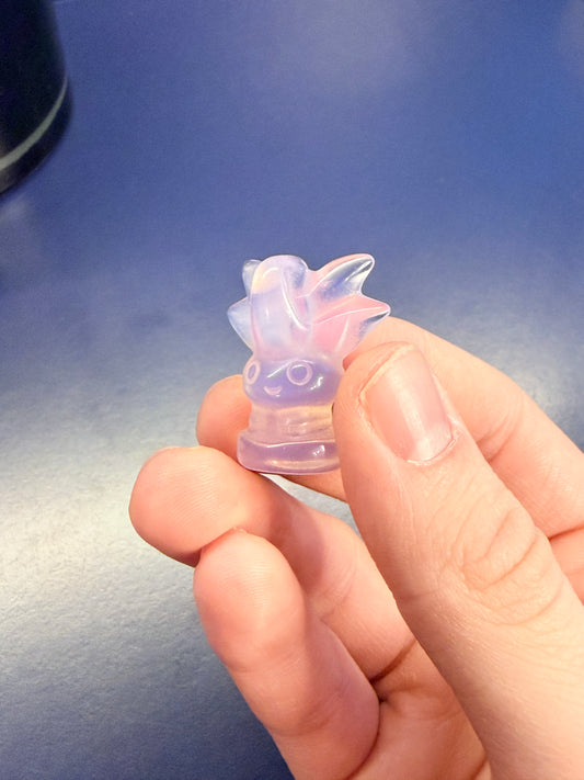 Hand holding translucent opalite oddish on blue background