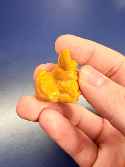 Hand holding an orange calcite flareon against a blue background