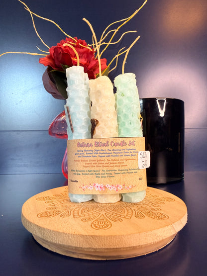 Three rolled candles with a label on a decorative wooden coaster in front of a red flower and black jar