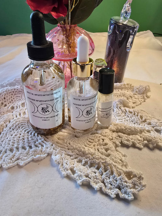Three glass bottles filled with clear body oil with herbs on a white crochet mat and white table cloth