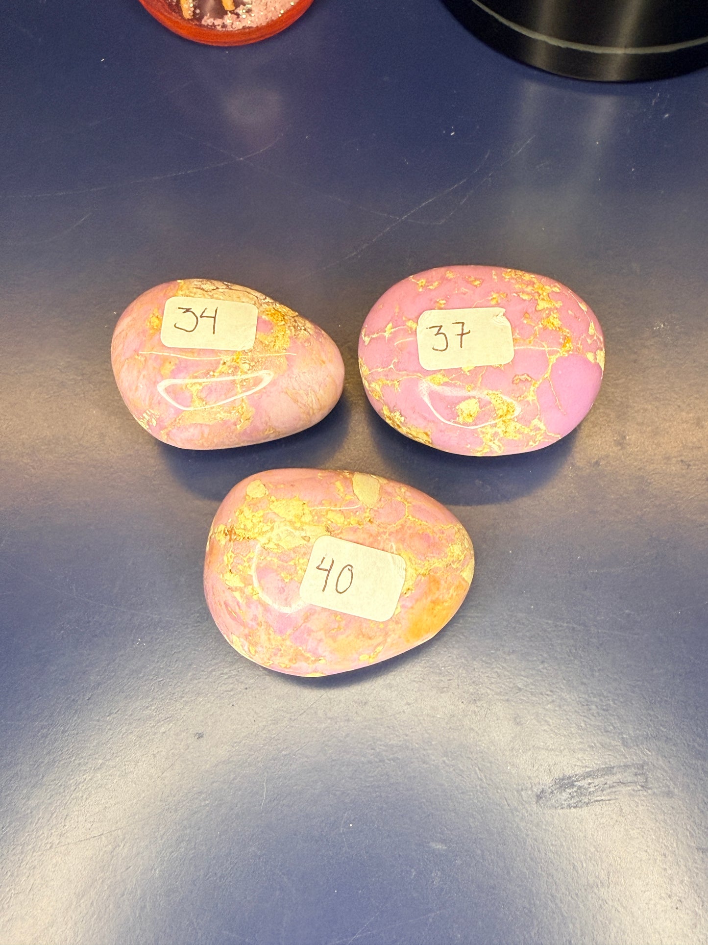Three pink and tan phosphosiderite palmstones on a blue background