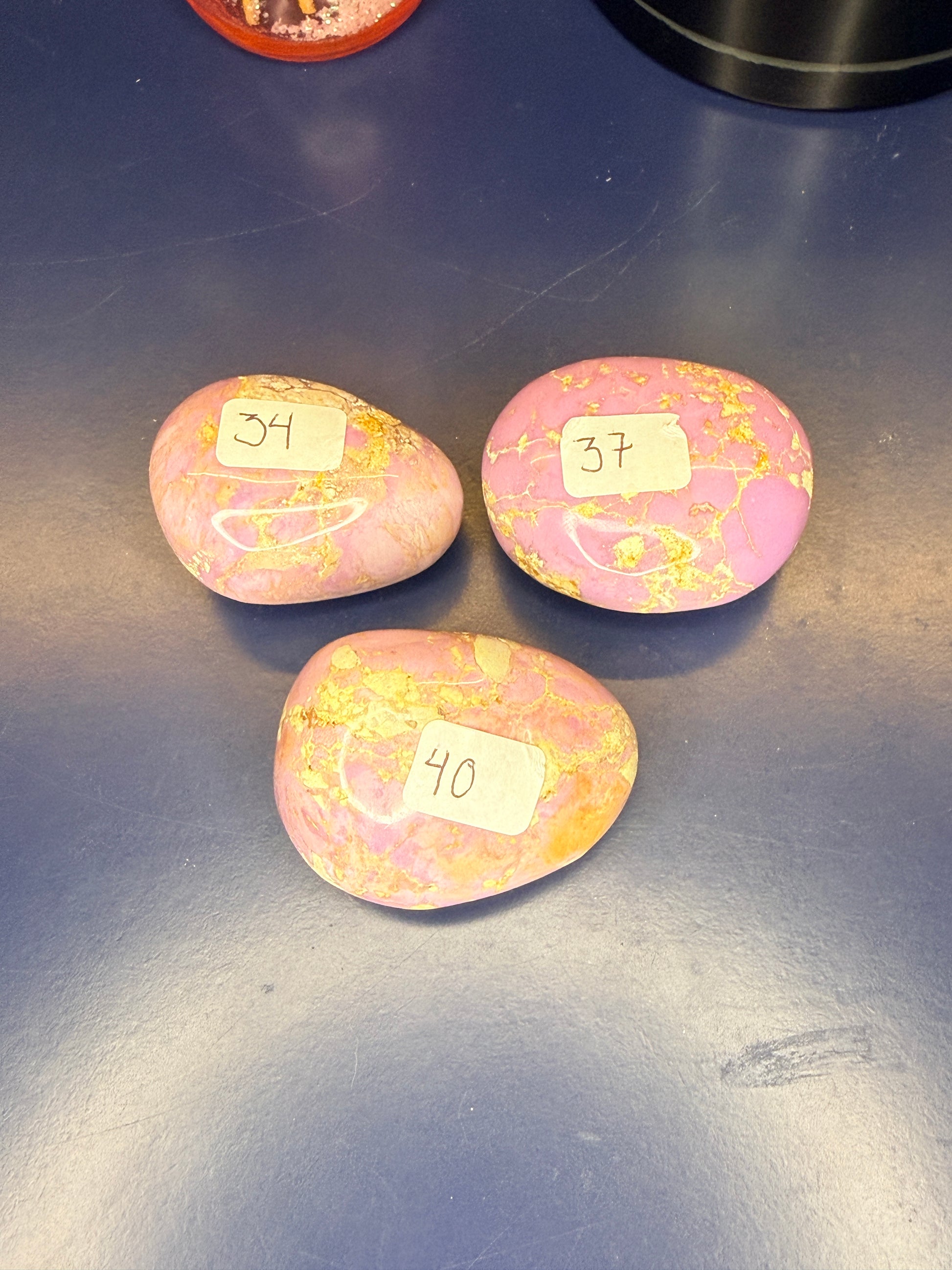 Three pink and tan phosphosiderite palmstones on a blue background