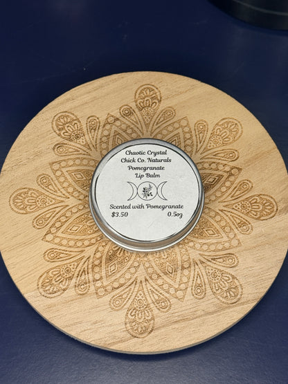 Circular labeled lip balm container on a decorative wooden coaster on a blue background