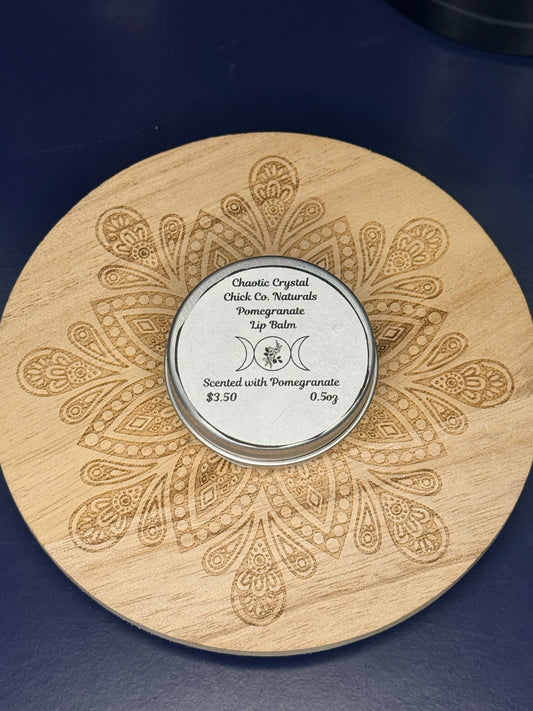 Circular labeled lip balm container on a decorative wooden coaster on a blue background