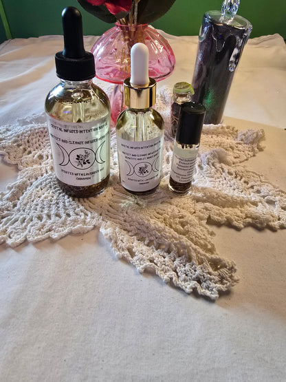 Three glass bottles filled with clear body oil with herbs on a white crochet mat and white table cloth