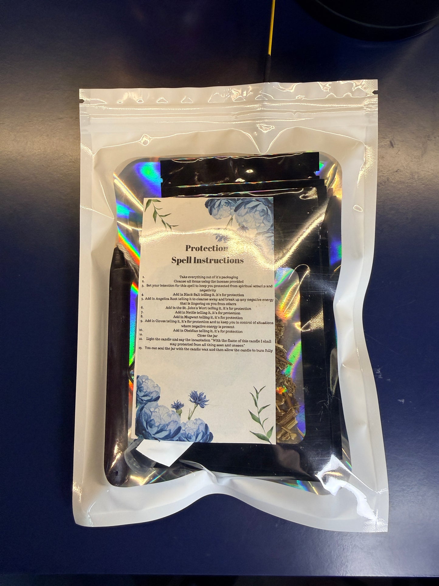 White plastic bag with a clear window showing a piece of decorative paper and smaller pouches on a blue background