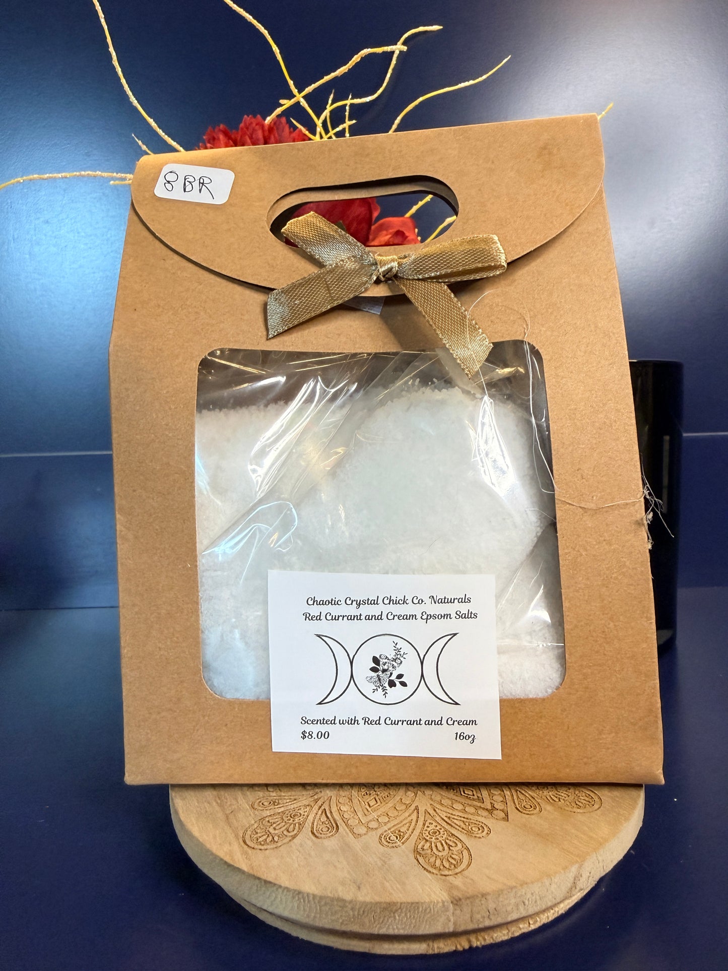 White epsom salt in a brown paper container with a bow, on a wooden coaster