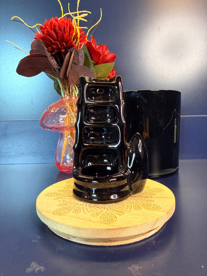 Black waterfall incense burner in front of a pink mushroom and black jar on a blue background