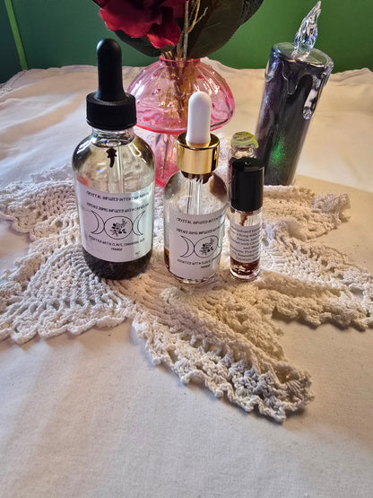 Three glass bottles filled with clear body oil with herbs on a white crochet mat and white table cloth