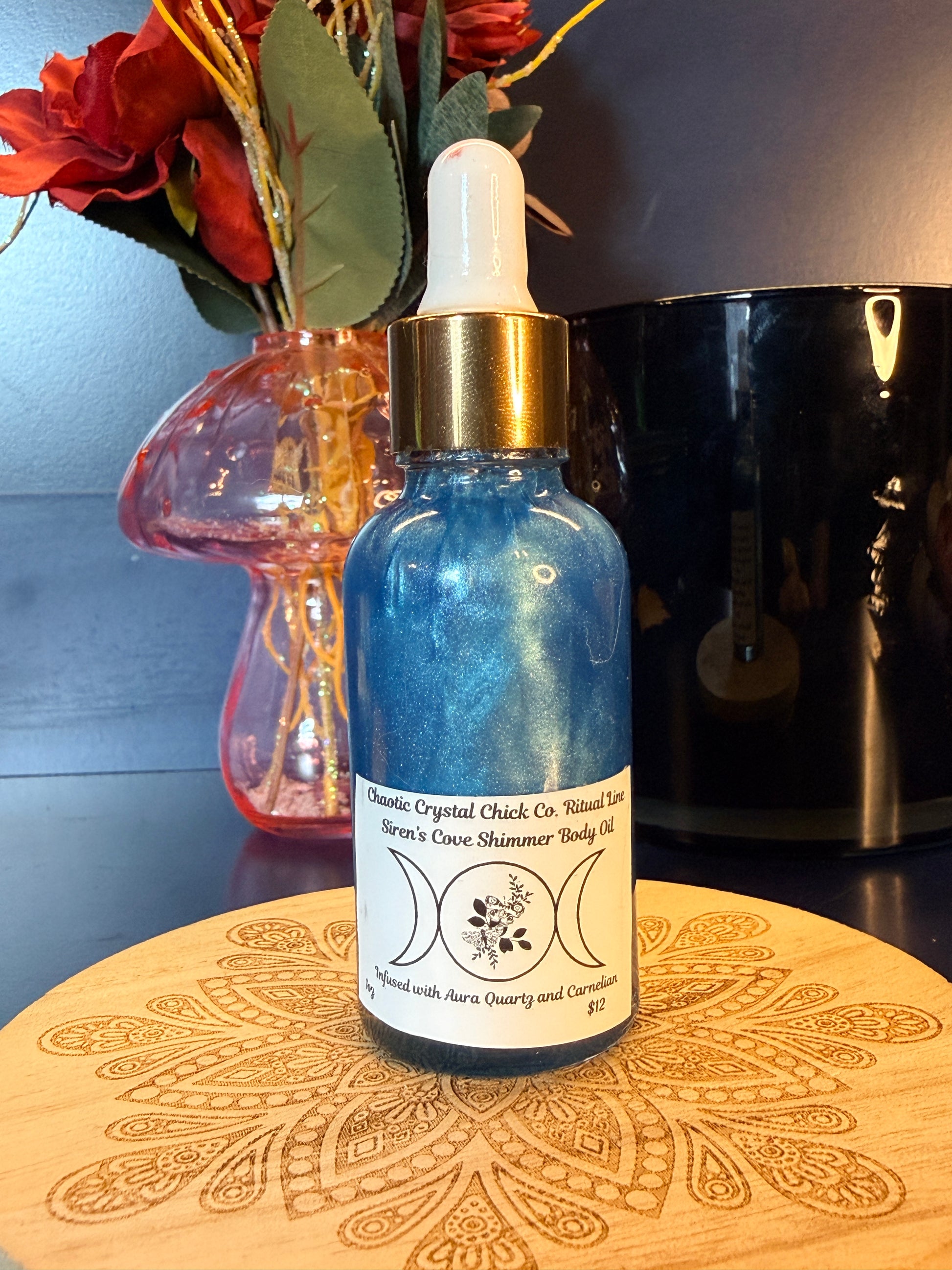 Blue bottle with gold cap on a decorative wooden coaster next to flowers