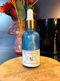 Blue bottle with gold cap on a decorative wooden coaster next to flowers