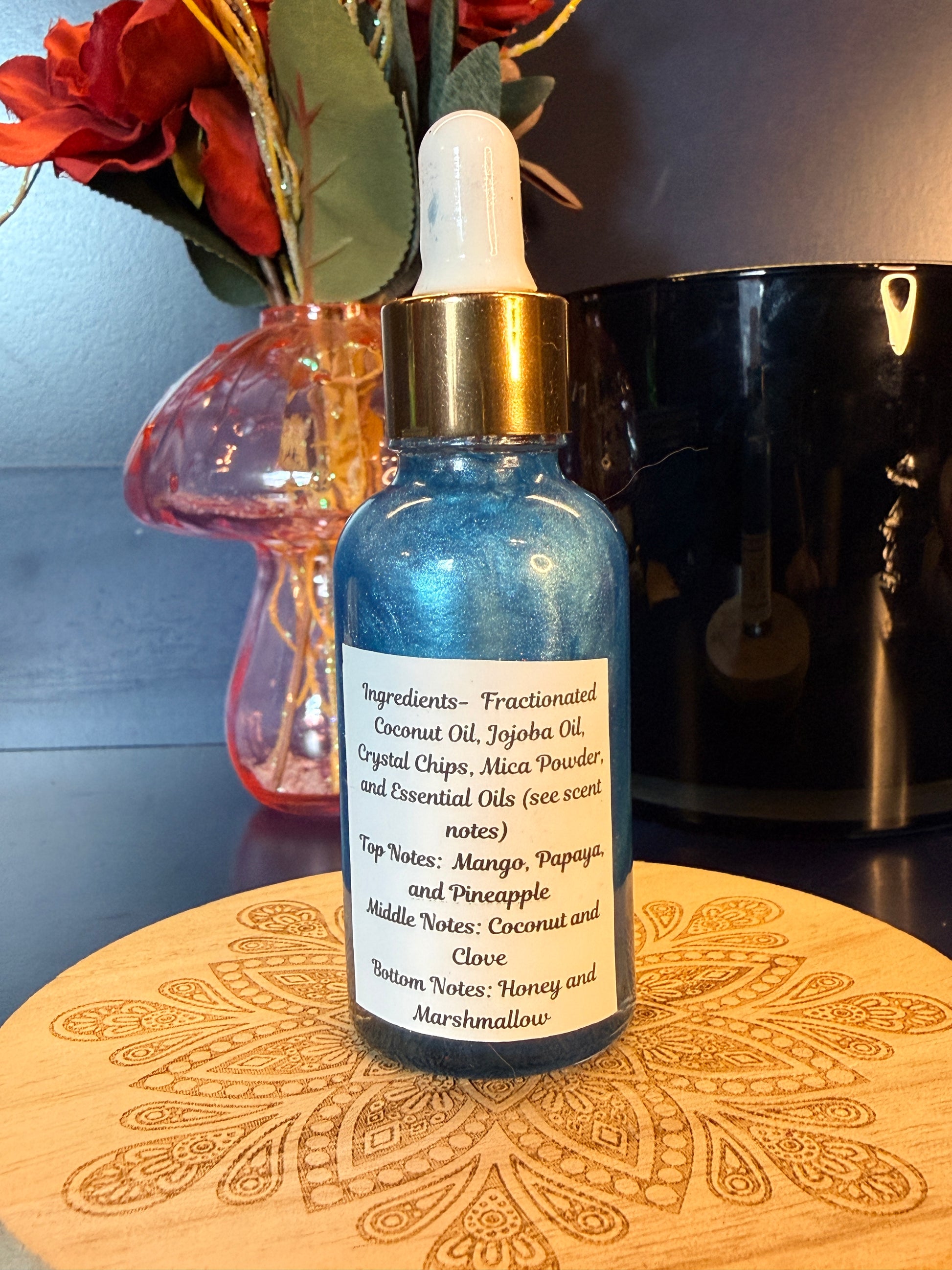 Blue bottle with gold cap on a decorative wooden coaster next to flowers
