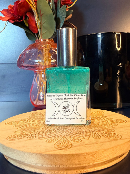 Perfume bottle with green liquid on a wooden surface with flowers and a black jar