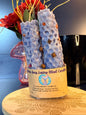 Two blue candles sitting on a decorative wooden coaster in front of a mushroom and black jar