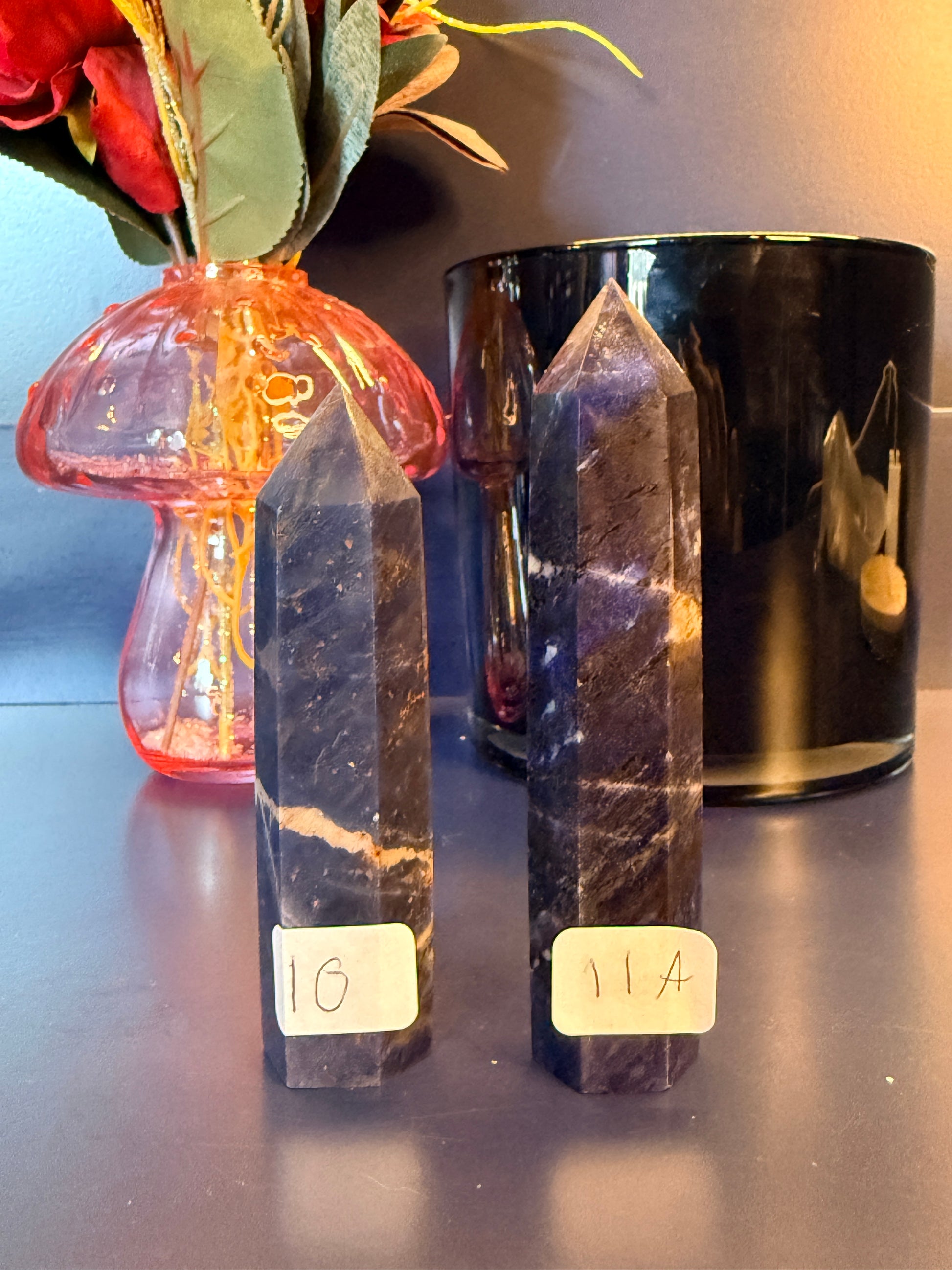 Two small blue crystal towers in front of a glass mushroom and black jar