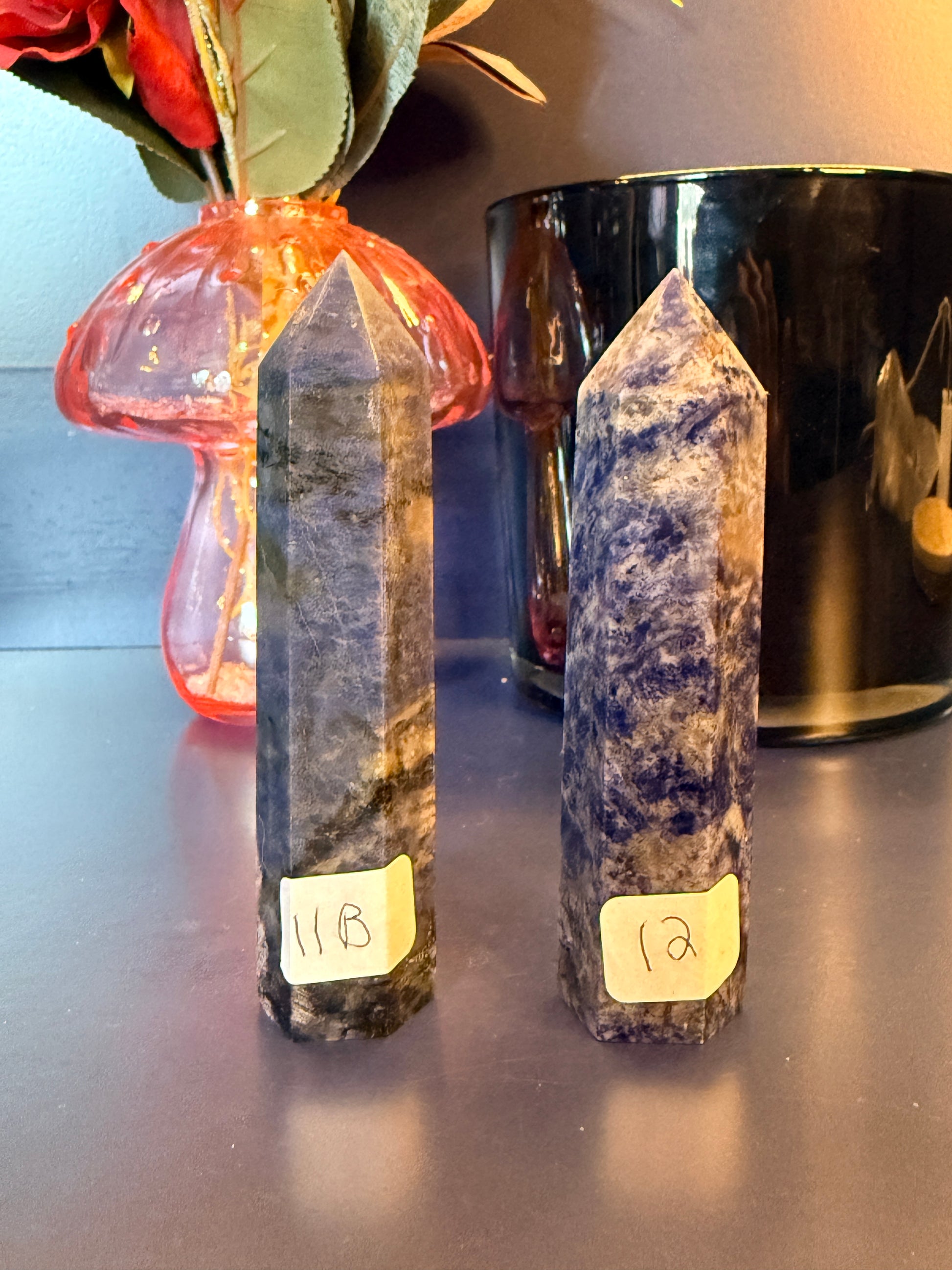 Two small blue crystal towers in front of a glass mushroom and black jar