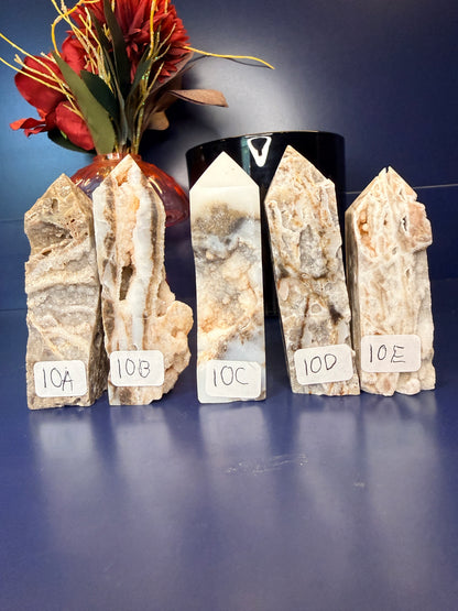 Five intricate sphalerite towers in front of a red flower in a vase and black jar on a blue background