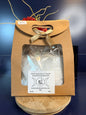 White epsom salt in a brown paper container with a bow, on a wooden coaster