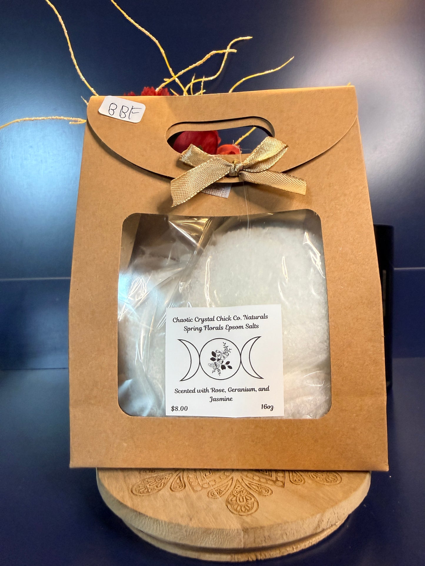 White epsom salt in a brown paper container with a bow, on a wooden coaster