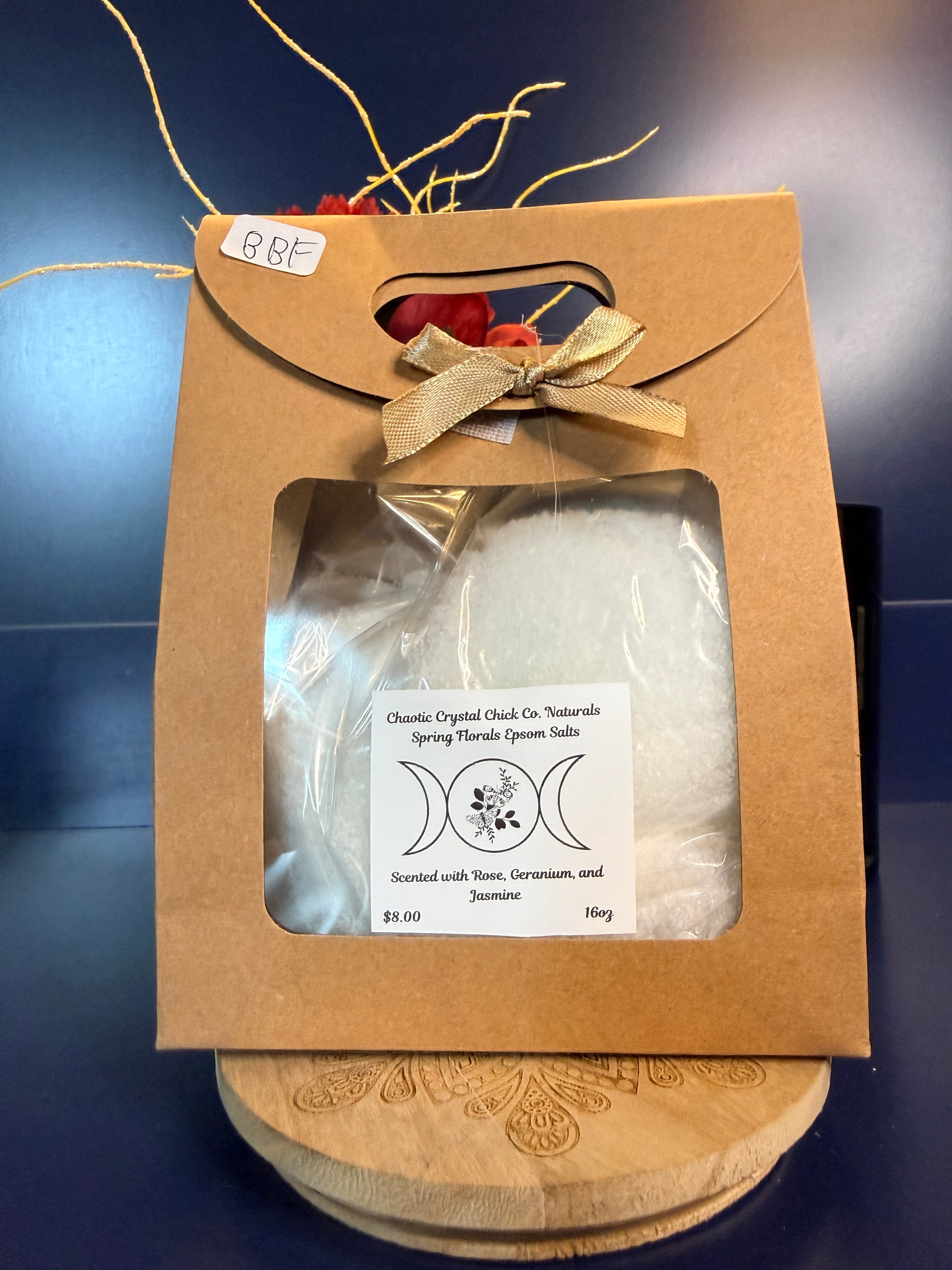 White epsom salt in a brown paper container with a bow, on a wooden coaster