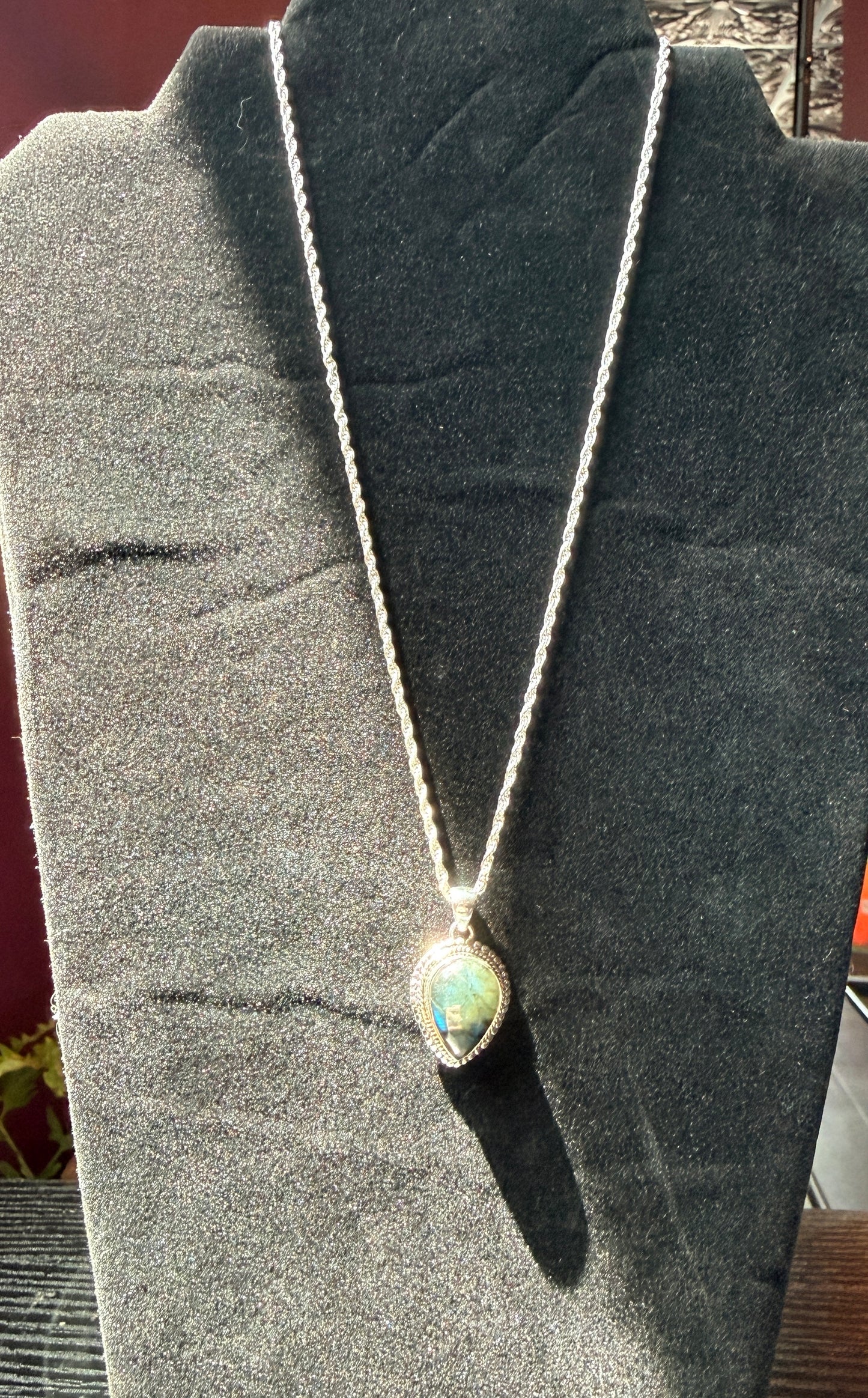 Sterling silver necklace resting on a black velvet jewelry stand holding a labradorite pendant