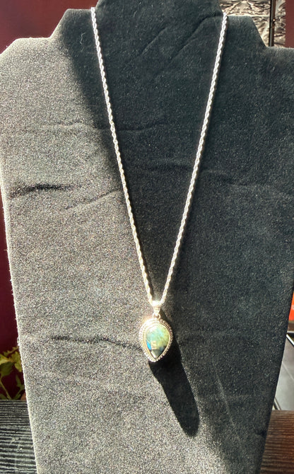 Sterling silver necklace resting on a black velvet jewelry stand holding a labradorite pendant